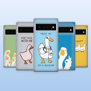 Puede incluir: Una colección de fundas para teléfonos con diseños de patos. Cada funda presenta una ilustración de pato diferente y una frase única, como "Trust Me I'm a Ducktor" y "Don't Duck With Me". Las fundas están disponibles en varios colores.