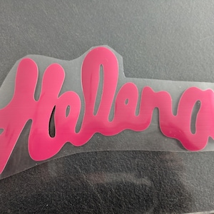 Peut inclure: Un autocollant en vinyle rose avec le nom "Hollana" écrit en cursive.