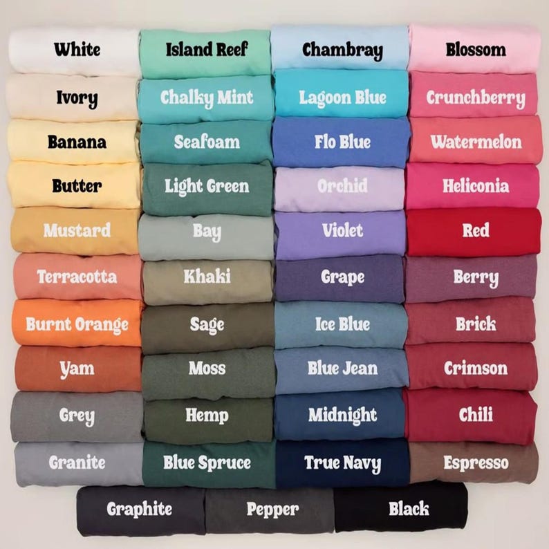 Op de afbeelding: Een raster van gevouwen t-shirts in verschillende kleuren, elk gelabeld met tekst waaronder White, Ivory, Banana, Butter, Mustard, Terracotta, Burnt Orange, Yam, Grey, Granite, Graphite, Island Reef, Chalky Mint, Seafoam, Light Green, Bay, Khaki, Sage, Moss, Hemp, Blue Spruce, Pepper, Chambray, Lagoon Blue, Flo Blue, Orchid, Violet, Grape, Ice Blue, Blue Jean, Midnight, True Navy, Blossom, Crunchberry, Watermelon, Heliconia, Red, Berry, Brick, Crimson, Chili, Espresso en Black.