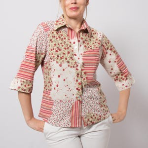 Peut inclure: Chemise à col avec un motif patchwork. La chemise présente un mélange de motifs floraux et rayés en rouge, blanc et beige. Les manches sont aux trois quarts et la chemise est boutonnée sur le devant.