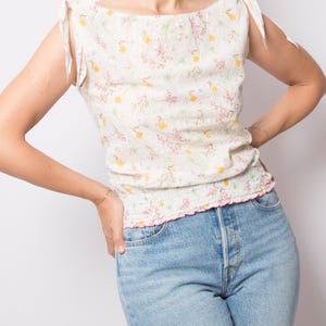 May include: A white ceramic mug with a black handle and the text "But First, Coffee" in a bold, black font. The mug is set against a blurred background, suggesting a cozy setting.