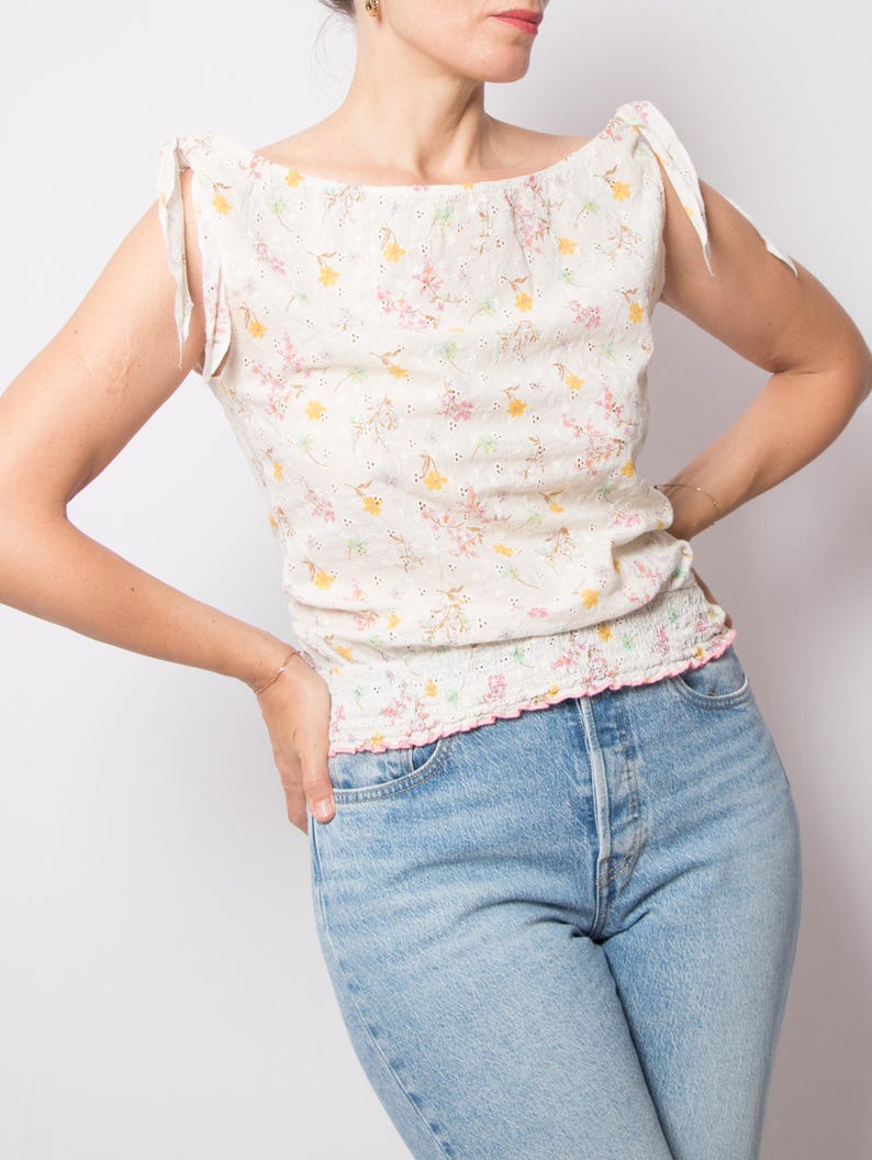 May include: A white ceramic mug with a black handle and the text "But First, Coffee" in a bold, black font. The mug is set against a blurred background, suggesting a cozy setting.