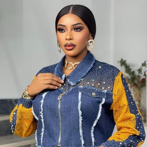 May include: A denim jacket with yellow lace sleeves and accents, embellished with rhinestones. The jacket has a zipper closure and is paired with a matching yellow lace top. Gold jewelry, including a necklace, earrings, and bracelets, completes the look.