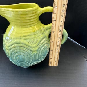 May include: A white ceramic mug with a black handle and the text "But First, Coffee" in a black, handwritten-style font. The mug is on a white surface.
