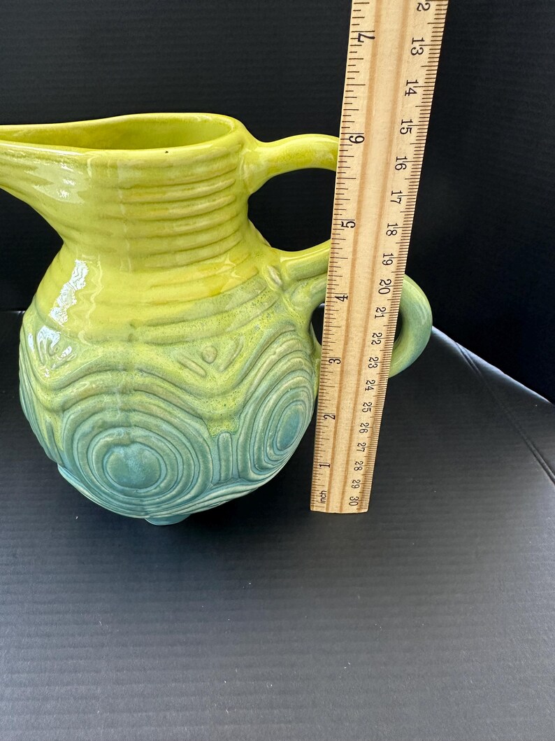 May include: A white ceramic mug with a black handle and the text "But First, Coffee" in a black, handwritten-style font. The mug is on a white surface.