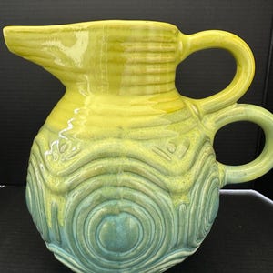 May include: A set of three ceramic canisters with lids, featuring a geometric pattern in shades of blue, white, and gray. The canisters vary in size, with the largest approximately 8 inches tall.