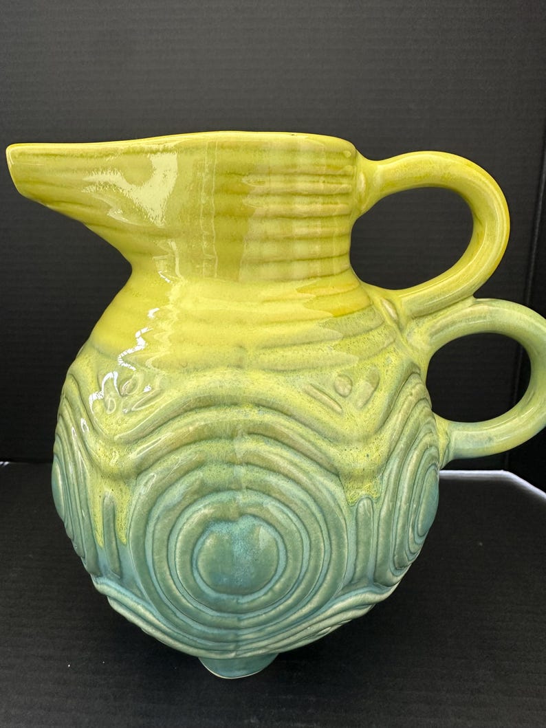 May include: A set of three ceramic canisters with lids, featuring a geometric pattern in shades of blue, white, and gray. The canisters vary in size, with the largest approximately 8 inches tall.