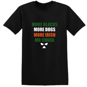 Könnte beinhalten: Schwarzes T-Shirt mit dem Text "MORE BLACKS MORE DOGS MORE IRISH MO CHARA" in Grün, Weiß und Orange. Unter dem Text befindet sich eine weiße Grafik eines Gesichts. Das T-Shirt hat einen Rundhalsausschnitt und kurze Ärmel.