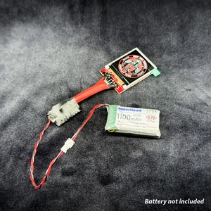 Könnte beinhalten: Elektronische Komponente mit einem rot-weißen Draht, einer Leiterplatte mit kreisförmigem Design und einem MakerHawk 1100 mAh Akku. Der Akku hat 3,7 V und 4,01 Wh. Der Text "Battery not included" steht unten.