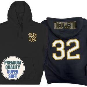 Pode incluir: Moletom preto com "TEAM LOGO" dourado na frente. A parte de trás apresenta "DEFAZIO" e o número "32" em branco com detalhes dourados. Um gráfico circular diz "PREMIUM QUALITY SUPER SOFT".