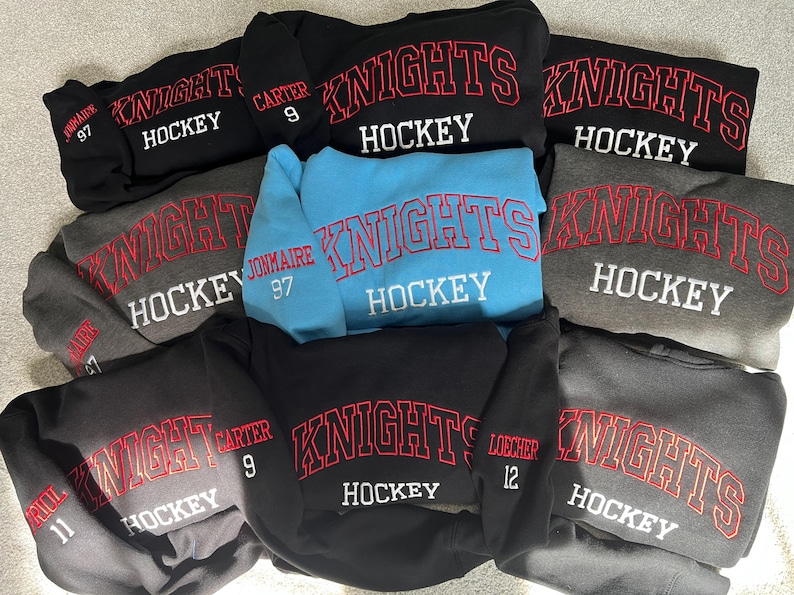 Puede incluir: Una colecci&oacute;n de sudaderas con tem&aacute;tica de hockey en varios colores, incluyendo negro, gris y azul claro. Cada sudadera presenta la palabra "KNIGHTS" en letras rojas arqueadas sobre "HOCKEY" en blanco. Algunas sudaderas tienen nombres y n&uacute;meros de jugadores.