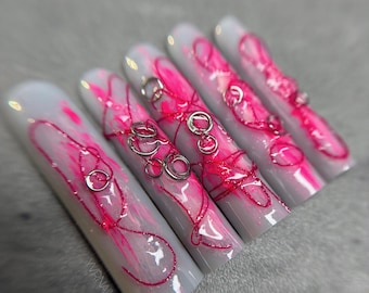 Uñas postizas abstractas de color rosa neón con dijes plateados, gel duro, hechas a mano, largas y cuadradas.
