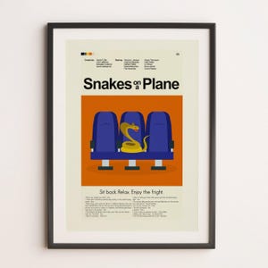 May include: Poster print featuring the movie title "Snakes on a Plane." The artwork depicts three blue airplane seats with a yellow snake coiled in the middle. The poster has a black frame and includes the tagline "Sit back. Relax. Enjoy the fright."