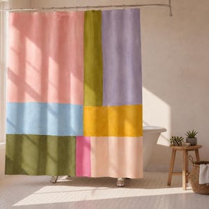 May include: A shower curtain featuring a colour-blocked pattern of rectangular shapes in shades of light pink, olive green, lavender, light blue, mustard yellow, and dark green, suspended from a metal rod with silver rings.