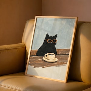 以下が含まれることがあります： オレンジ色のメガネをかけた黒猫が、コーヒーカップの置かれたテーブルに座っているフレーム付きアートプリント。アートワークは水色の背景と木製のフレームで、気まぐれな美学を作り出しています。