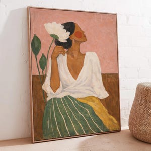 May include: A framed painting depicting a person with dark hair wearing a white wrap top and a green and yellow striped skirt. The person holds a large white flower near their head against a pink and brown background with green leaves.