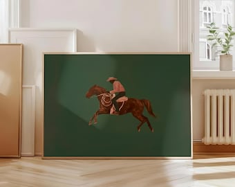 May include: A framed art print depicts a cowboy riding a brown horse against a dark green background. The cowboy wears a pink shirt and a hat. The horse is mid-jump, with a rope visible.