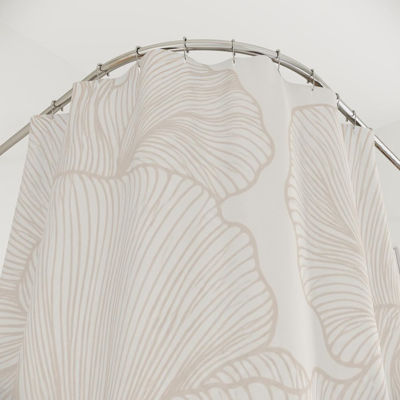 May include: A white shower curtain featuring a large-scale, repeating ginkgo leaf pattern in a soft beige line-art style. The curtain is suspended from a curved, polished silver metal rod by a series of matching silver metal shower curtain rings.