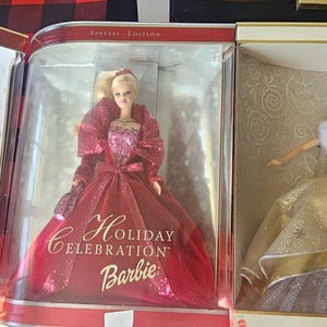 Puede incluir: Tres muñecas Barbie en sus cajas originales. Las muñecas visten elaborados vestidos, uno en rojo y dorado, uno en rojo y otro en dorado. Las cajas están etiquetadas como "Happy Holidays", "Holiday Celebration" y "2000 Edition".