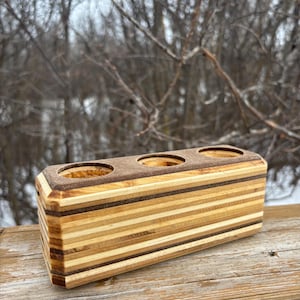 May include: A wooden organiser with three circular holes, made from layered wood with a natural wood finish.