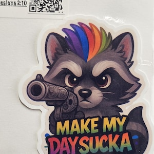 Peut inclure: Autocollant représentant un raton laveur de dessin animé avec une crête arc-en-ciel, tenant un pistolet. Le texte "MAKE MY DAY SUCKA" est écrit en lettres colorées de style graffiti. L'autocollant a une bordure blanche.