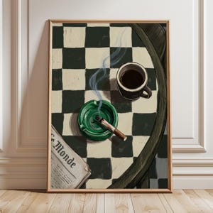 May include: A framed print featuring a still life with a green ashtray holding a lit cigarette, a black coffee mug, and a newspaper with the text "Le Monde". The background is a black and white checkered pattern.