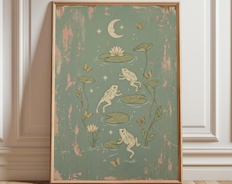 May include: A framed art print featuring a whimsical pond scene. The artwork depicts three frogs on lily pads, surrounded by butterflies, a crescent moon, and a water lily. The background is a distressed green with pink accents.