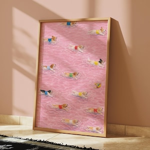 May include: A framed art print featuring a repeating pattern of dogs swimming in a pink pool. The dogs are wearing colorful life vests. The print is in a wooden frame and leans against a pink wall.