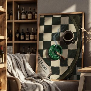 May include: A framed artwork featuring a green and white checkered pattern, a cup of coffee, a lit cigarette in a green ashtray, and a newspaper. The artwork is displayed in a room with a wooden shelf filled with bottles.