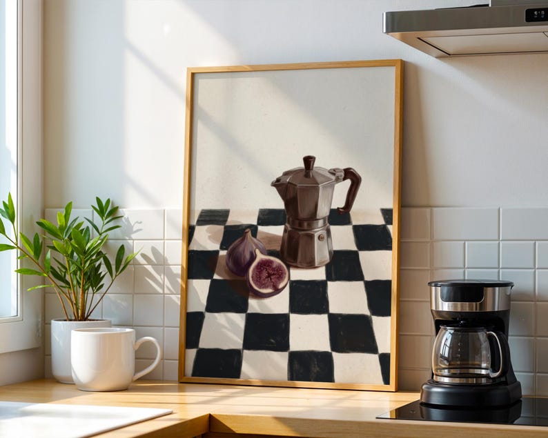 May include: A framed print featuring a still life with a brown stovetop espresso maker, figs, and a black and white checkered pattern. A coffee maker and a mug are in the foreground.