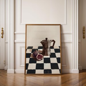 May include: A framed print featuring a still life composition. The artwork depicts a dark brown stovetop espresso maker, two figs, one sliced, on a black and white checkered tablecloth. The frame is a warm brown color.