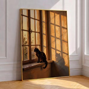 May include: A framed wall art print depicting a black cat sitting on a wooden windowsill in front of a large window. The scene is illuminated by warm, golden sunlight casting grid-like shadows across the wall and the cat's silhouette.