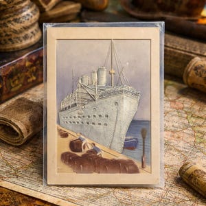 Könnte beinhalten: Vintage Postkarte mit einem großen weißen Kreuzfahrtschiff, das an einem Pier angedockt hat. Die Illustration zeigt zwei Figuren, die Gepäck verladen. Die Postkarte befindet sich in einer Schutzhülle mit einem beigen Rand. Der Hintergrund umfasst eine Karte und andere Vintage-Artikel.