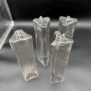 May include: Five clear glass prism pendants with a textured surface and silver metal loops. The prisms are shaped like a long rectangle with a triangular top.