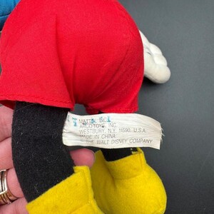 May include: A vintage Mickey Mouse plush toy, featuring red shorts, black legs, yellow shoes, and white gloves. The tag reads "MATTEL INC ARCO TOYS, INC. WESTBURY, N.Y. 11590, U.S.A. MADE IN CHINA THE WALT DISNEY COMPANY."