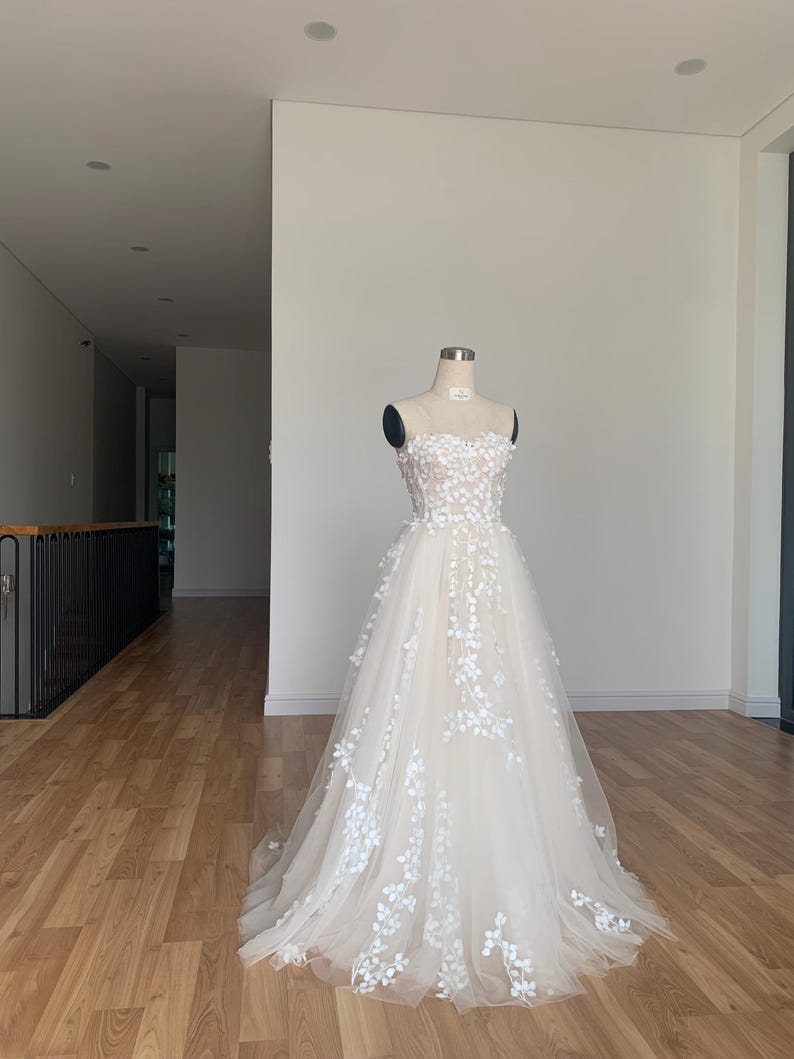 Step into your dream garden wedding with the enchanting Flower Gown, a masterpiece of elegance and bohemian charm. Imagine yourself adorned in delicate lace, flowing gracefully with every step as you make your way down the aisle. The Flower Gown is meticulously crafted to capture the essence of romance. Its intricate lace detailing exudes timeless allure, while its boho-inspired design ensures you stand out on your special day. Slip into the Flower Gown and embrace your fairy tale moment.