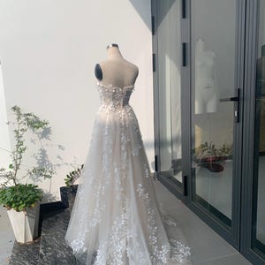 Step into your dream garden wedding with the enchanting Flower Gown, a masterpiece of elegance and bohemian charm. Imagine yourself adorned in delicate lace, flowing gracefully with every step as you make your way down the aisle. The Flower Gown is meticulously crafted to capture the essence of romance. Its intricate lace detailing exudes timeless allure, while its boho-inspired design ensures you stand out on your special day. Slip into the Flower Gown and embrace your fairy tale moment.