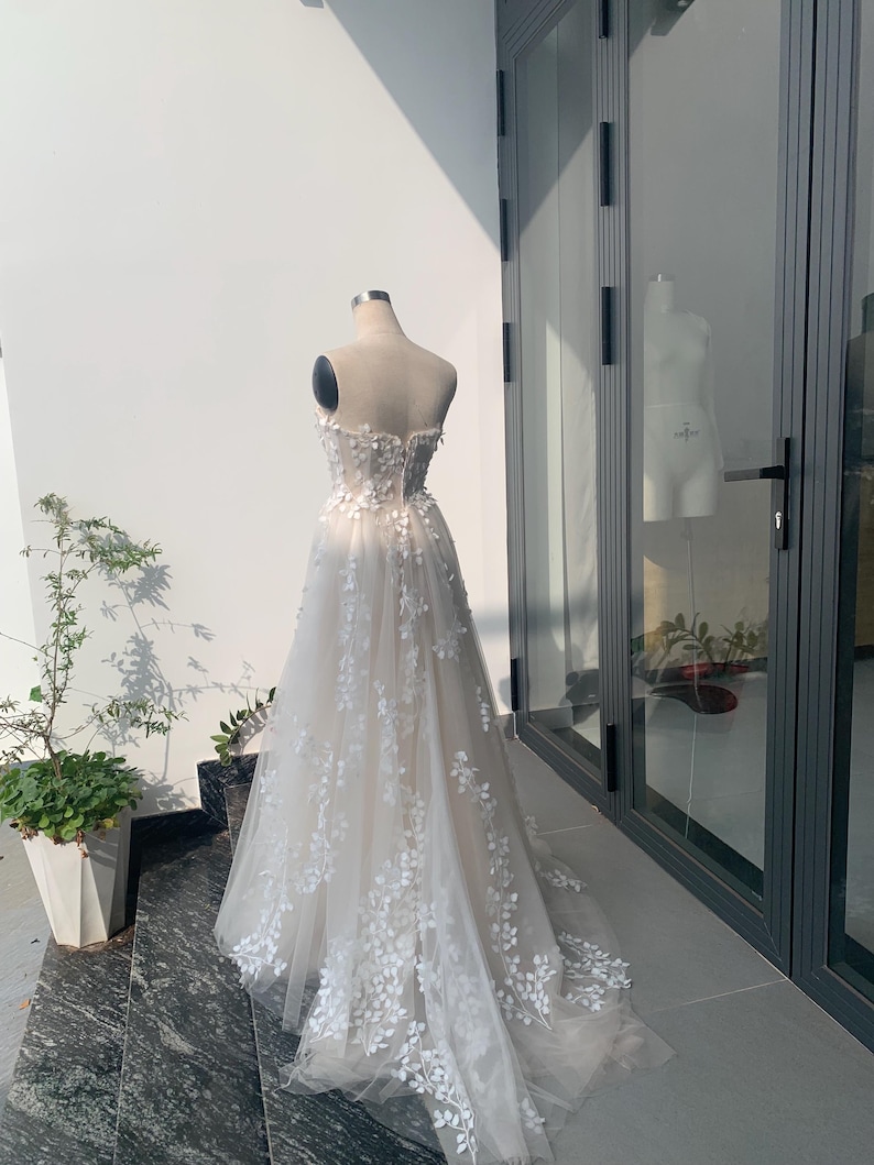 Step into your dream garden wedding with the enchanting Flower Gown, a masterpiece of elegance and bohemian charm. Imagine yourself adorned in delicate lace, flowing gracefully with every step as you make your way down the aisle. The Flower Gown is meticulously crafted to capture the essence of romance. Its intricate lace detailing exudes timeless allure, while its boho-inspired design ensures you stand out on your special day. Slip into the Flower Gown and embrace your fairy tale moment.