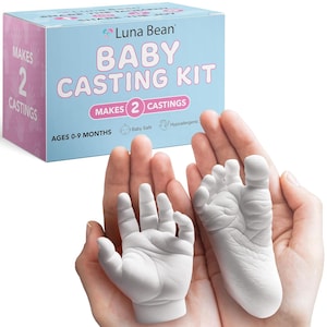 May include: A baby casting kit with a hand and foot cast. The kit box is light blue and white, with the words "Baby Casting Kit" and "Makes 2 Castings." The casts are white and held in open hands. The kit is for ages 0-9 months and is baby safe and hypoallergenic.