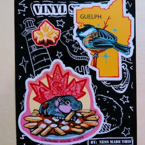 May include: Black vinyl sticker with cartoon illustrations of a hippo eating fries, a bird with a crown, and a maple leaf. The sticker also includes a lighthouse and the text "VINYL STICKERS", "Guelph", and "CANADIAN HOUSE HIPPO".