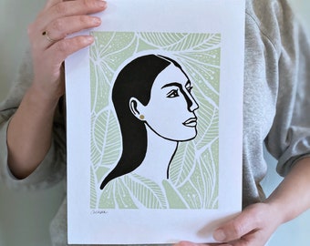 Limited edition linocut print of woman surrounded with flowers, printed in soft green and black