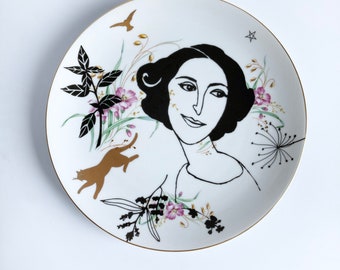 Antique plate screenprinted with female portrait and other details in black and gold, illustrated by Celinda. diameter 24 cm
