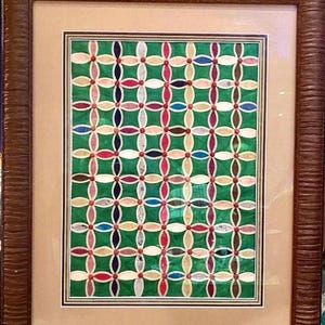 Puede incluir: Una obra de arte enmarcada que presenta un patrón geométrico colorido hecho de papel. El patrón está compuesto por círculos y óvalos superpuestos en tonos de rojo, verde, azul, rosa y blanco, creando un diseño visualmente atractivo e intrincado.