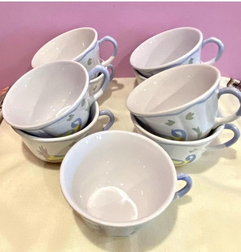 Pu&ograve; includere: Set di sei tazze da t&egrave; in ceramica bianca con motivi floreali blu e verdi. Le tazze hanno una forma arrotondata e un manico sul lato.