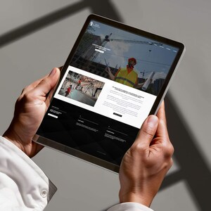 May include: A tablet showing a website for a carpentry and building contractor. The site includes images of construction sites and a construction worker in a hard hat and safety vest. The tablet is held by a person wearing a white shirt.
