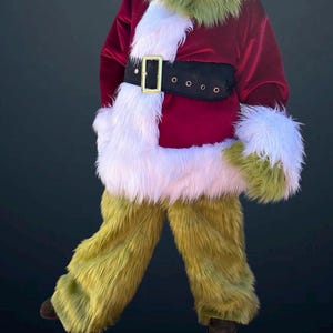 May include: A festive costume featuring a red velvet jacket with white faux fur trim and a black belt with a gold buckle. The costume includes green furry pants and matching green furry gloves and collar, creating a whimsical holiday look.