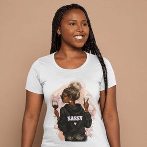 Könnte beinhalten: Weißes T-Shirt mit einem Aufdruck einer Frau, die ein Glas Wein hält, und dem Wort "SASSY" auf ihrem Rücken.