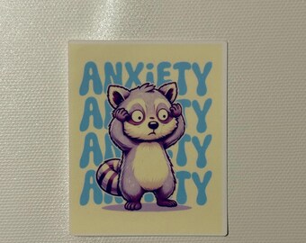 May include: A square sticker featuring a cartoon raccoon with wide eyes and hands covering its ears. The word "ANXIETY" is written in blue, stylized text. The raccoon is in shades of gray, purple, and white, set against a yellow background.