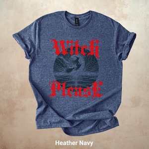 May include: Heather navy blue t-shirt with the text "Witch Please" in red gothic lettering. The design features a witch flying on a broomstick in front of a dark blue circle. The shirt is a crew neck.