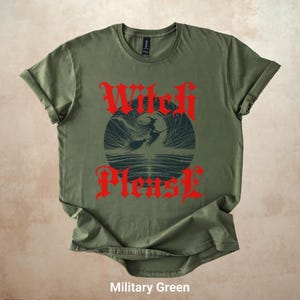 May include: Military green t-shirt with the text "Witch Please" in red gothic font. The shirt features a dark blue graphic of a witch riding a broom over water. The shirt is made of a soft material.